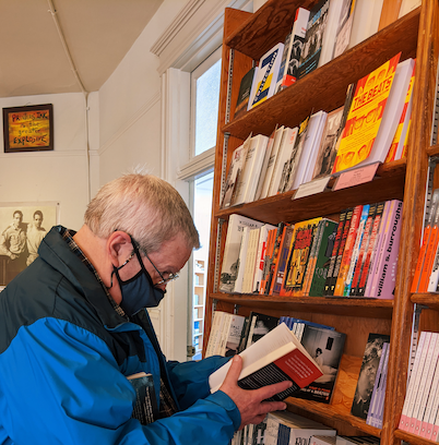 The Director of Our Phoenix Foundation, the curator of a vast collection of male survivor memoirs and literary works, captured in a powerful image amidst books at a random bookstore.