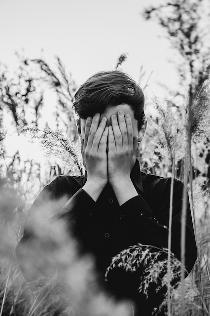 image of teen boy with hands over his face